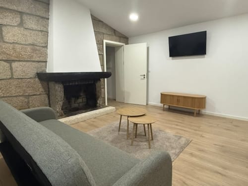 Modern living room at Casa dos Vasconcelos cottage in Chaves with fireplace, TV, seating, and wooden flooring