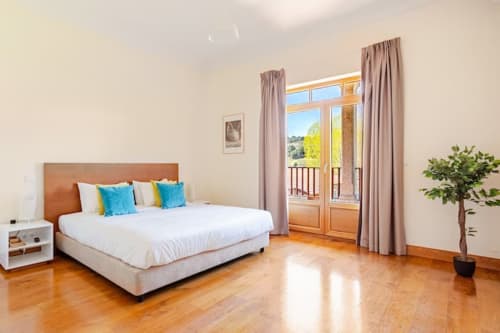Bright bedroom at Casa dos Vasconcelos, Chaves BnB, with bed, terrace doors, hardwood floors, and modern amenities