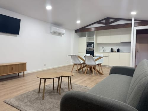 Modern cottage living area in Casa dos Vasconcelos, Chaves with dining table, sofa, kitchen, and TV