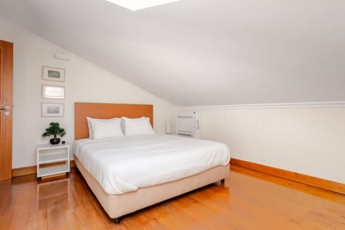 Bright bedroom at Casa dos Vasconcelos in Chaves with orange headboard, white bedding, wooden floors, and modern amenities