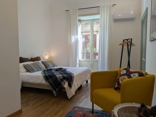 Camera da letto moderna al BnB del Parlamento Palermo con balcone, poltrona color senape e affaccio sulla città