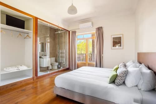 Spacious bedroom at Casa dos Vasconcelos in Chaves with en-suite bathroom, wooden floors, balcony access, and modern