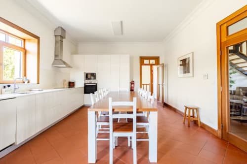 Modern cottage kitchen-dining area at Casa dos Vasconcelos in Chaves with white cabinetry, terracotta floors, and wooden