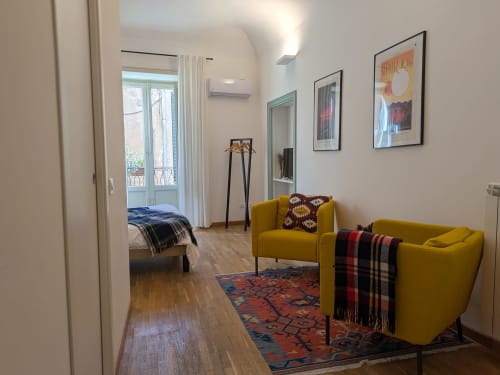 Moderna camera doppia con poltrone gialle, accesso al balcone e vista sulla città al BnB del Parlamento Palermo Sicilia
