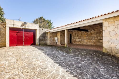 Stone cottage courtyard in Chaves with red garage doors and covered patio area