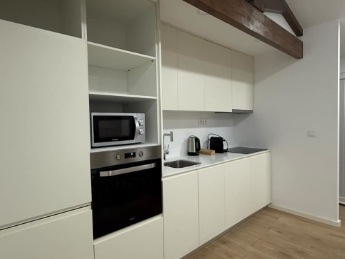 Modern kitchen in Casa dos Vasconcelos cottage, Chaves Portugal. White cabinets, stainless steel appliances, microwave,