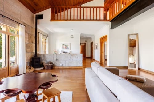 Spacious open-plan living area at Casa dos Vasconcelos cottage in Chaves with wooden beams, fireplace, white sofa and dining