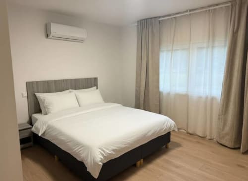 Modern bedroom at Casa dos Vasconcelos in Chaves with queen bed, air conditioning, and sheer curtains overlooking natural