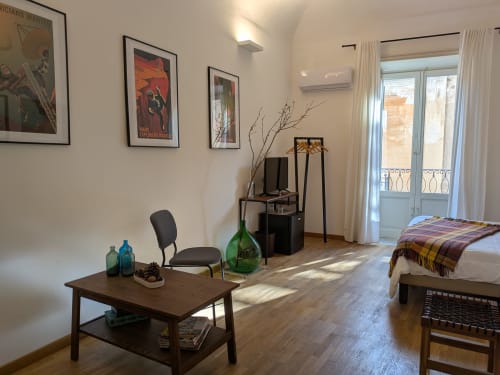 Luminosa camera tripla nel B&B di Palermo con mobili in legno, balcone con vista sulla città, comfort moderni e quadri alle pareti bianche
