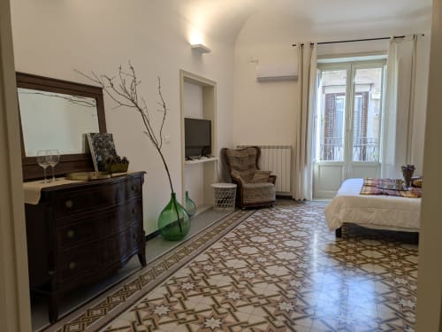 Spaziosa camera da letto con balcone presso BnB del Parlamento Palermo, con cassettone in legno scuro, pavimento in piastrelle decorate e vista sulla città