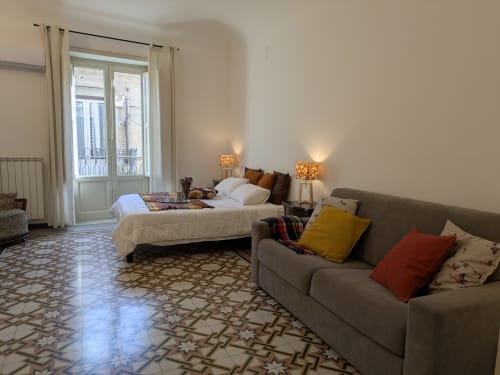 Spaziosa camera da letto presso BnB del Parlamento Palermo con letto, divano, vista dal balcone e pavimento in ceramica decorata