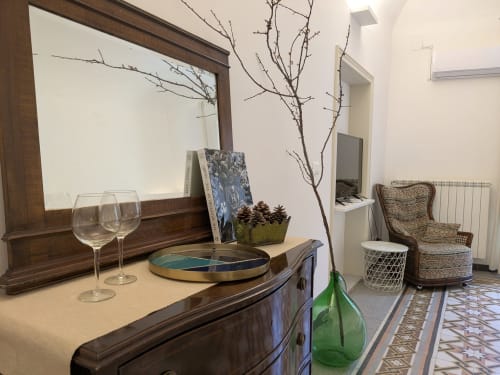 Camera da letto elegante al BnB del Parlamento Palermo con mobili in legno, specchio, rami decorativi e sedia in vimini