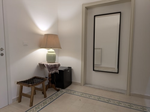 Ingresso elegante di BnB del Parlamento Palermo con specchio, lampada, panchina in legno e pavimento in piastrelle decorative