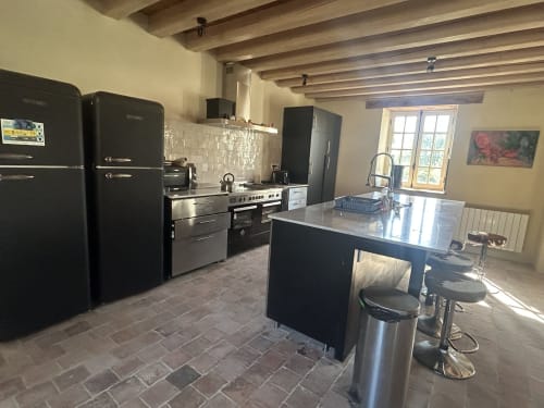 Cuisine contemporaine à la Cour Du Liège B&B avec électroménagers noirs, îlot en acier inoxydable et poutres apparentes à Baugé-en-Anjou