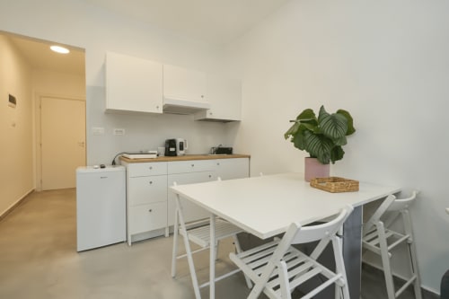 Cucina e zona pranzo moderne dell'appartamento a Rozzano con tavolo bianco, sedie, angolo cottura attrezzato e pianta in vaso