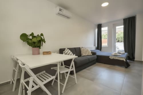Moderno soggiorno con tavolo da pranzo bianco, divano antracite e porte scorrevoli affacciate sul balcone a Rozzano