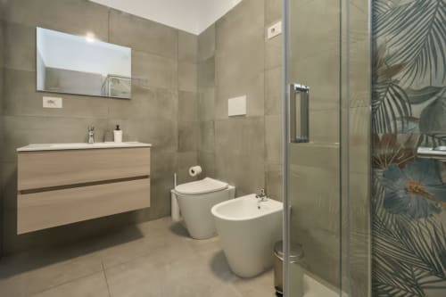 Bagno moderno nell'appartamento AirFlat di Rozzano con lavabo, toilette, bidet e doccia con piastrelle a motivi botanici