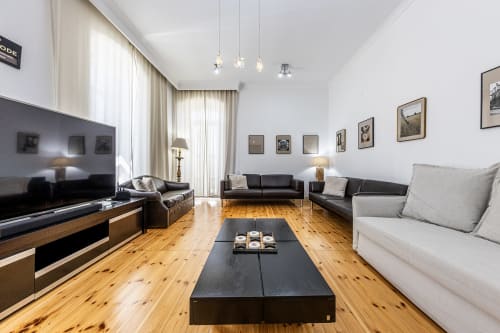 Modern living room at Alojamento CSA in Camarnal with wooden floors, black and white sofas, pendant lights, and framed