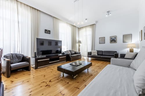 Ampla sala de estar da villa com mobiliário em couro, TV de ecrã plano, pavimento em madeira e janelas luminosas no Alojamento CSA