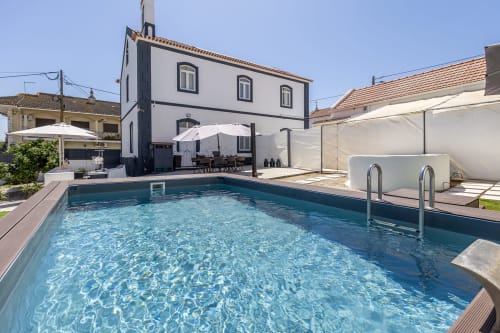 Vila privada rural em Camarnal com piscina azul, guarda-sóis brancos e arquitetura moderna