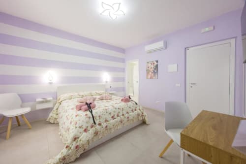 Camera Doppia Standard Vittoria presso La Maison Du Lion B&B a La Spezia con pareti a righe viola, biancheria floreale e arredamento moderno