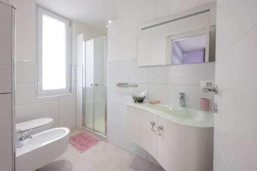 Bagno moderno nella camera Vittoria di La Maison Du Lion B&B, La Spezia con piastrelle bianche, lavabo, specchio e zona doccia