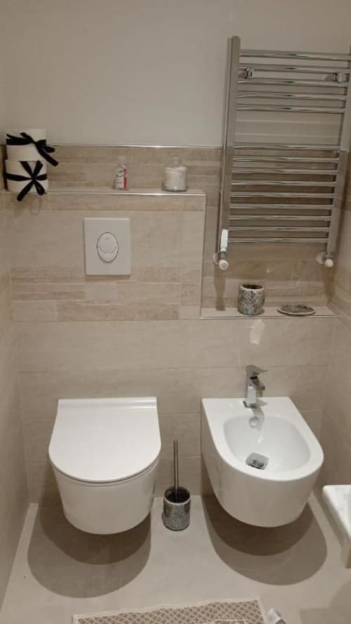 Bagno moderno con toilette e bidet bianchi in La Maison Du Lion B&B, La Spezia, con scaldasalviette cromato e rivestimenti in piastrelle
