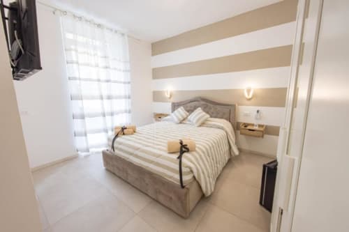 Camera doppia Perla a La Maison Du Lion di La Spezia con letto a righe, strisce orizzontali alle pareti e balcone con vista giardino