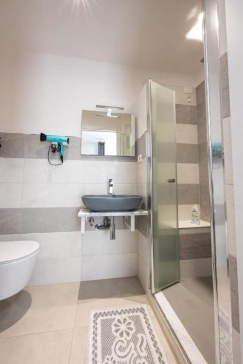 Bagno moderno nella camera Perla di La Maison Du Lion B&B, La Spezia, con piastrelle grigie, lavabo tondo e doccia in vetro