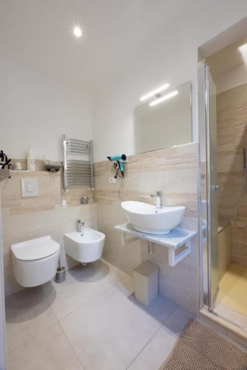 Bagno moderno in La Maison Du Lion, La Spezia con arredi bianchi, lavabo a bacinella, wc sospeso, bidet e doccia aperta