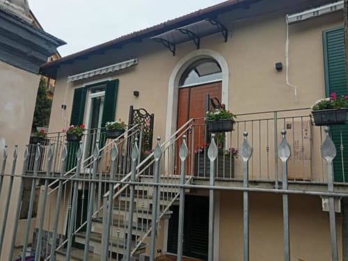 Balcone della La Maison Du Lion B&B a La Spezia con portale ad arco, fioriere fiorite e ringhiera metallica che affaccia sul giardino