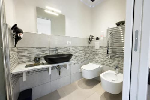 Bagno moderno a La Maison Du Lion con lavabo nero a coppa, wc e bidet bianchi, piastrelle a strisce e scaldasalviette