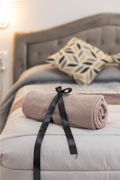 Asciugamano beige arrotolato con nastro nero sulla biancheria bianca nella Doppia Perla di La Maison Du Lion, La Spezia