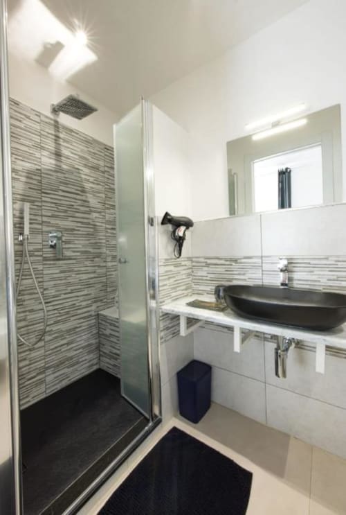 Bagno moderno della camera Luna Double a La Maison Du Lion B&B, La Spezia, con doccia a piastrelle righe, lavabo nero e