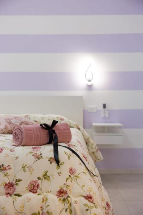 Accogliente camera con lenzuola floreali e asciugamano rosa arrotolato presso La Maison Du Lion B&B a La Spezia, Italia