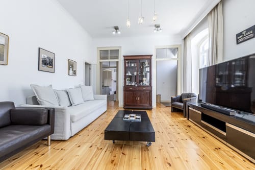 Bright living room at Alojamento CSA, Camarnal with wood floors, white sofa, TV, and dark furniture