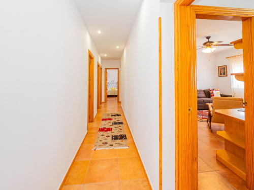 Pasillo luminoso con puertas de madera y azulejos de terracota en la villa Alhaurín Loft City Center