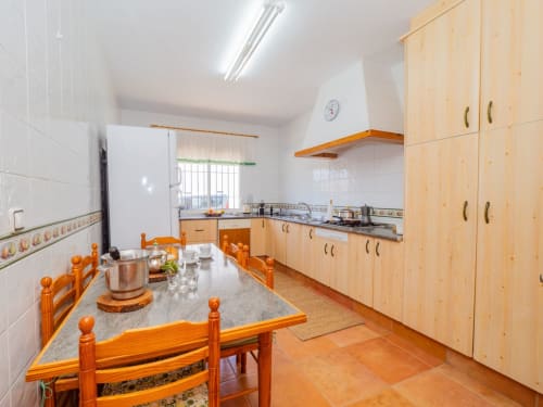 Cocina amplia con gabinetes de madera, mesa de comedor y suelo de barro naranja en la villa Alhaurín Loft