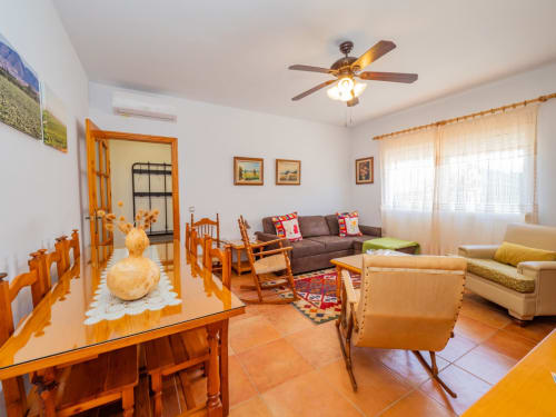 Amplio salón de la villa Alhaurín Loft con muebles de madera, sofá marrón, ventilador de techo y suelo de baldosas de terracota