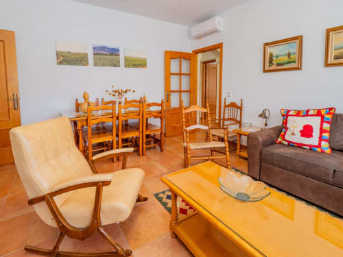 Amplio salón en Alhaurín Loft con muebles de madera, sillón color crema, sofá, mesa de comedor y suelo de barro
