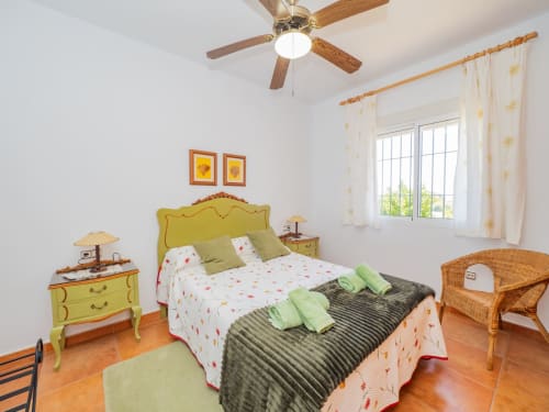 Dormitorio luminoso en Alhaurín Loft con cabecero amarillo, almohadas verdes y suelo de terracota
