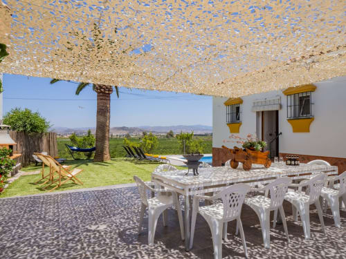Terraza exterior con mesa de comedor blanca, tumbonas, palmera y vistas a las montañas en la villa Alhaurín Loft