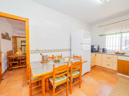 Luminosa zona de cocina-comedor en villa Alhaurín Loft con muebles de madera, electrodomésticos blancos y suelos de baldosas de terracota
