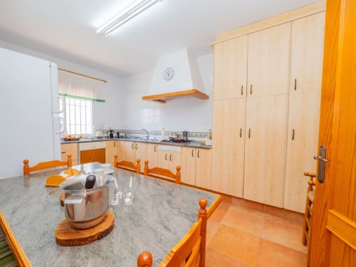 Amplia cocina de villa en Alhaurín Loft con muebles de madera clara, encimeras grises y detalles naranjas.