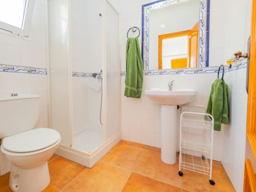 Baño moderno en Alhaurín Loft con lavamanos de pedestal blanco, ducha, azulejos naranjas y toallas verdes