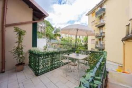 Terrazza esterna di La Maison du Lion B&B a La Spezia con vista giardino, tavolo da pranzo, ombrellone e ringhiere ricoperte di edera