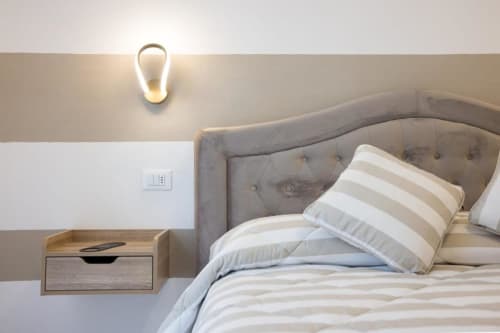 Camera da letto moderna a La Maison du Lion con letto imbottito grigio, cuscini rigati e applique contemporaneo a La Spezia