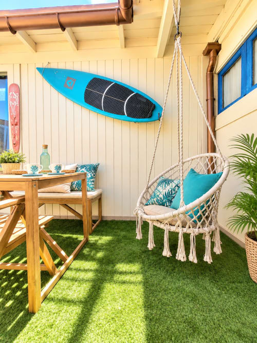 Patio affacciato sul mare con altalena in macramé, kayak blu, tavolo da pranzo in legno e piante tropicali a Sara & Gino Fuerteventura