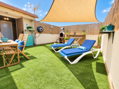 Soleggiata terrazza sul tetto dell'appartamento Sara & Gino Corralejo con lettini, erba artificiale, vela ombreggiante gialla e muri in mattoni