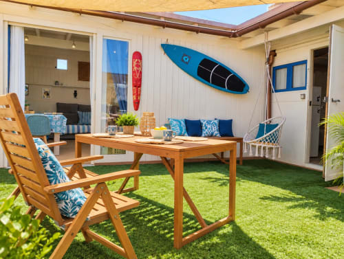 Patio dell'appartamento fronte mare con tavolo da pranzo in legno, sedie a sdraio, kayak blu e tenda retrattile a Corralejo